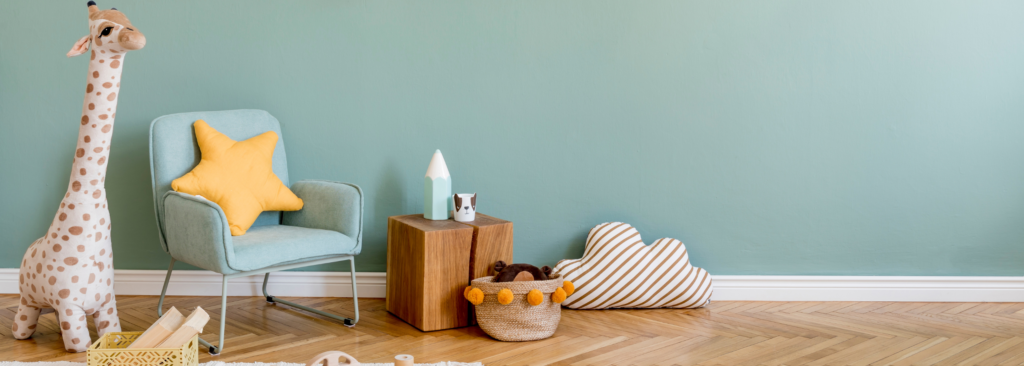 Kinderzimmer. Minzfarbende Wand und Minzfarbender Sessel. Giraffenkuscheltier.